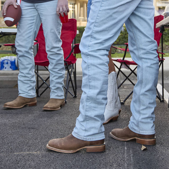 A group of young adults wearing Justin Boots while tailgating at a football game.